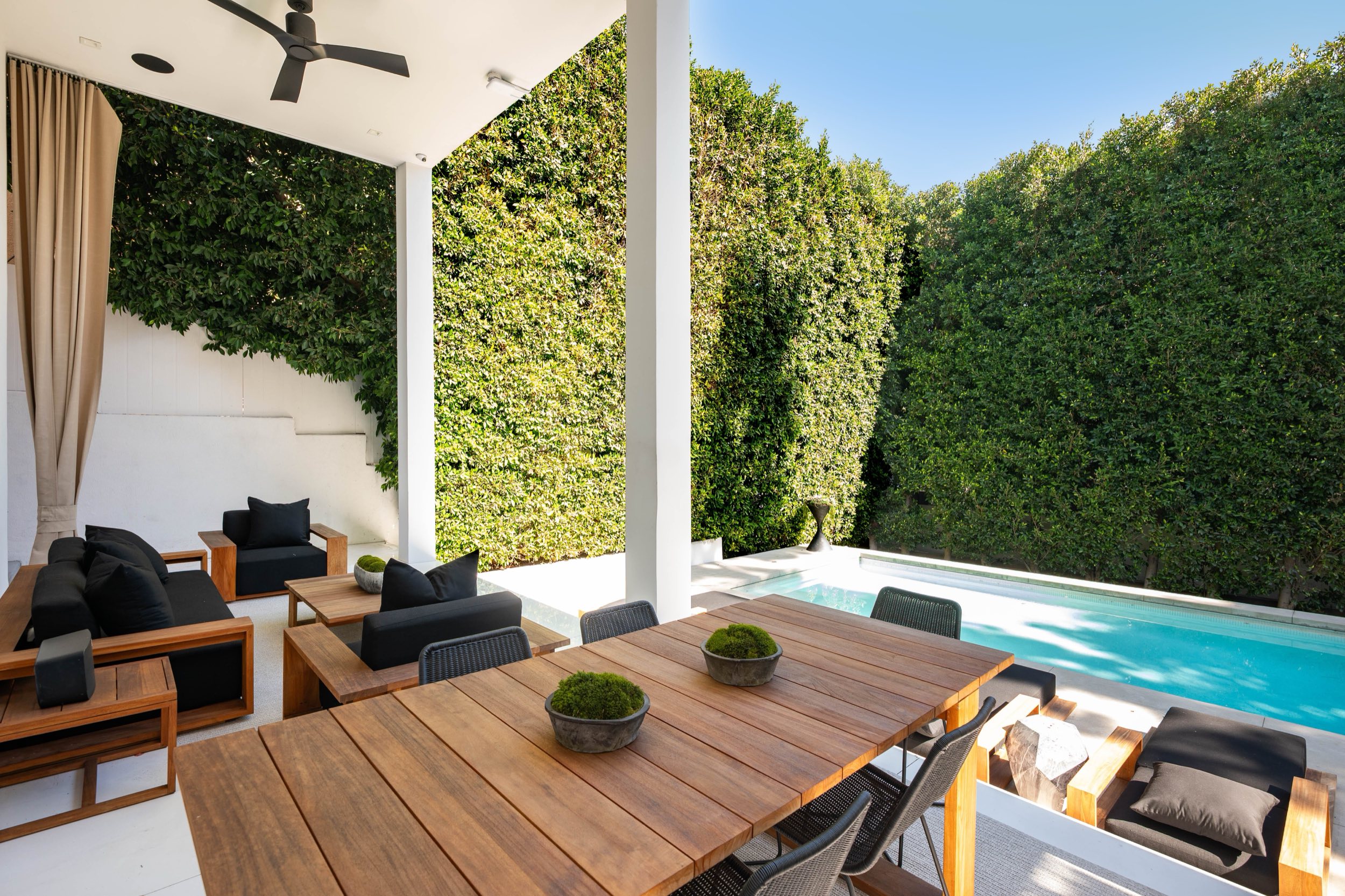 Covered outdoor dining terrace beside the pool at twilight