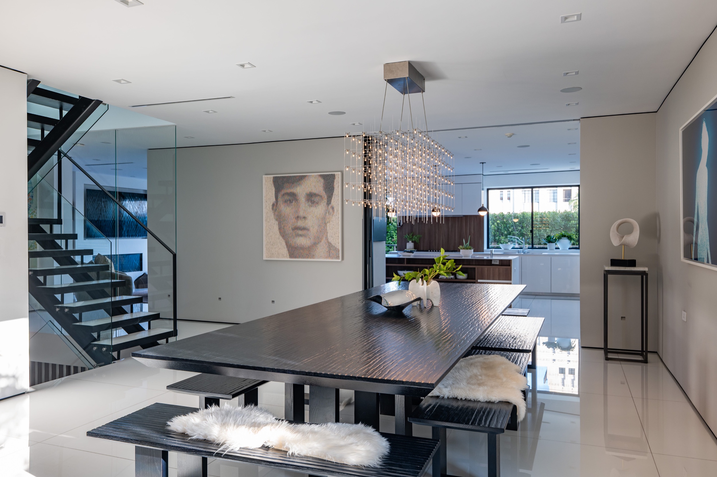 Dining table with the open stairwell beside it and the kitchen beyond