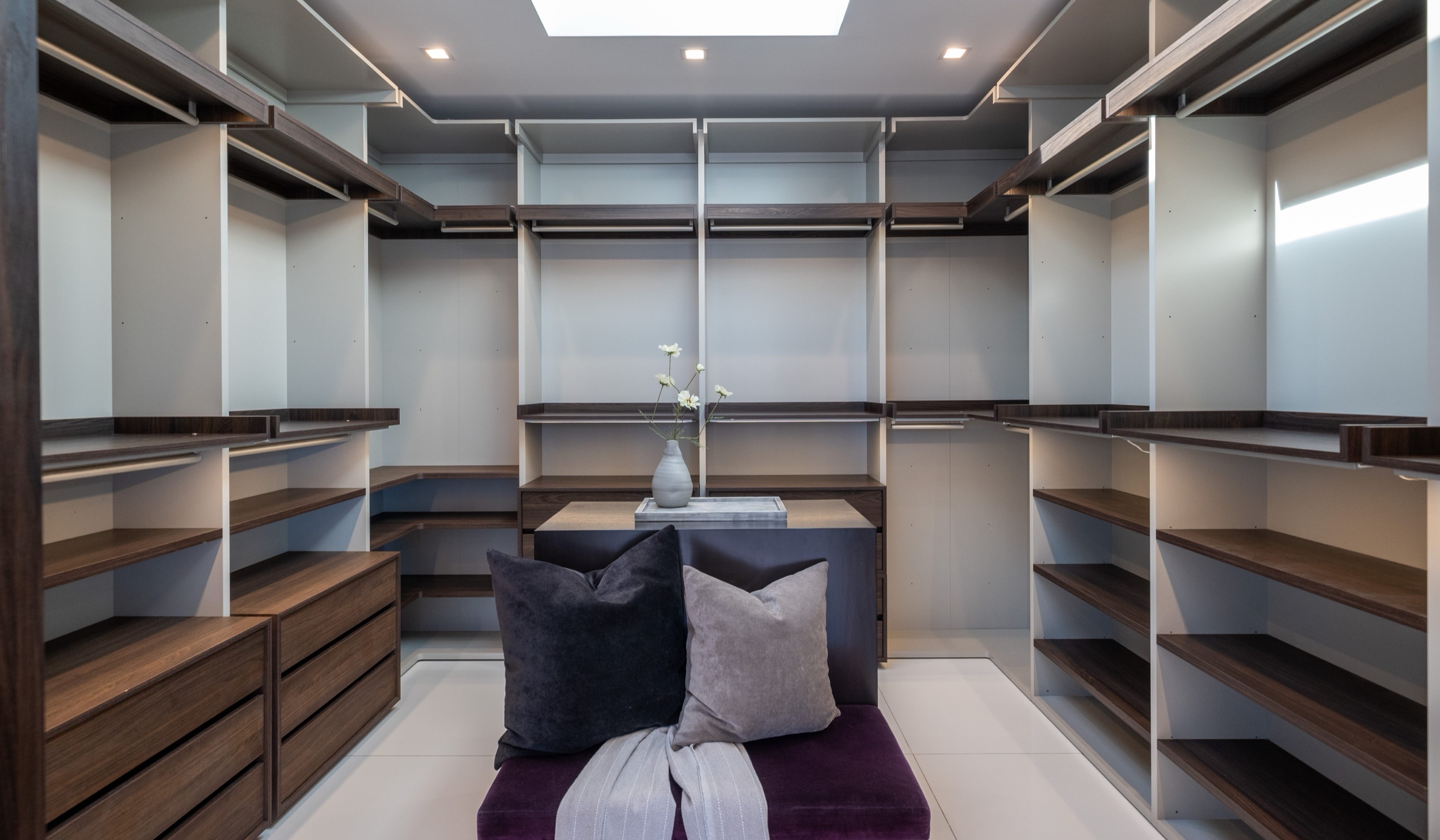 Dressing room with custom cabinetry, island and upholstered bench