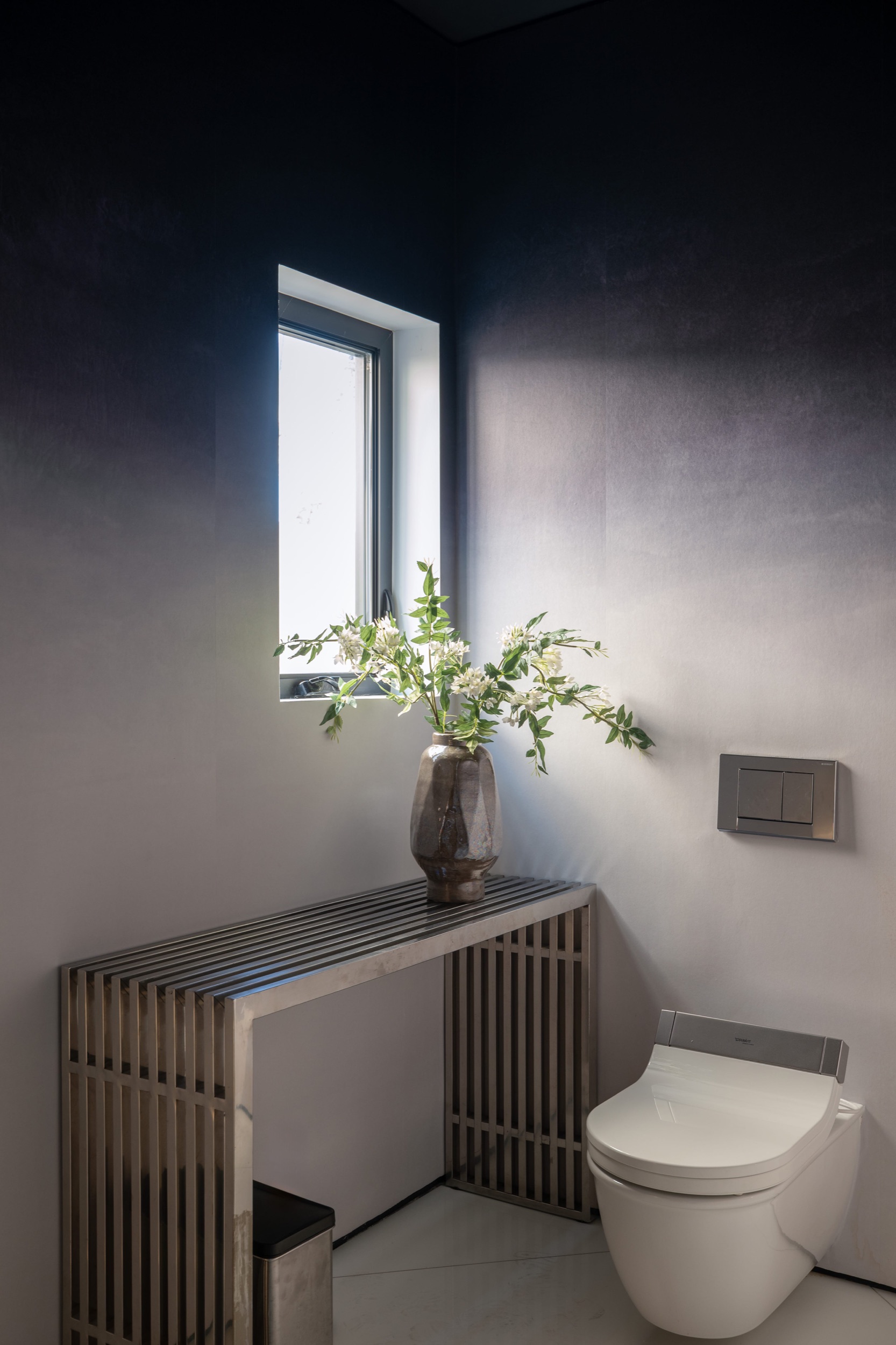 Powder room detail: branches in a stone vase on the bench beside the window