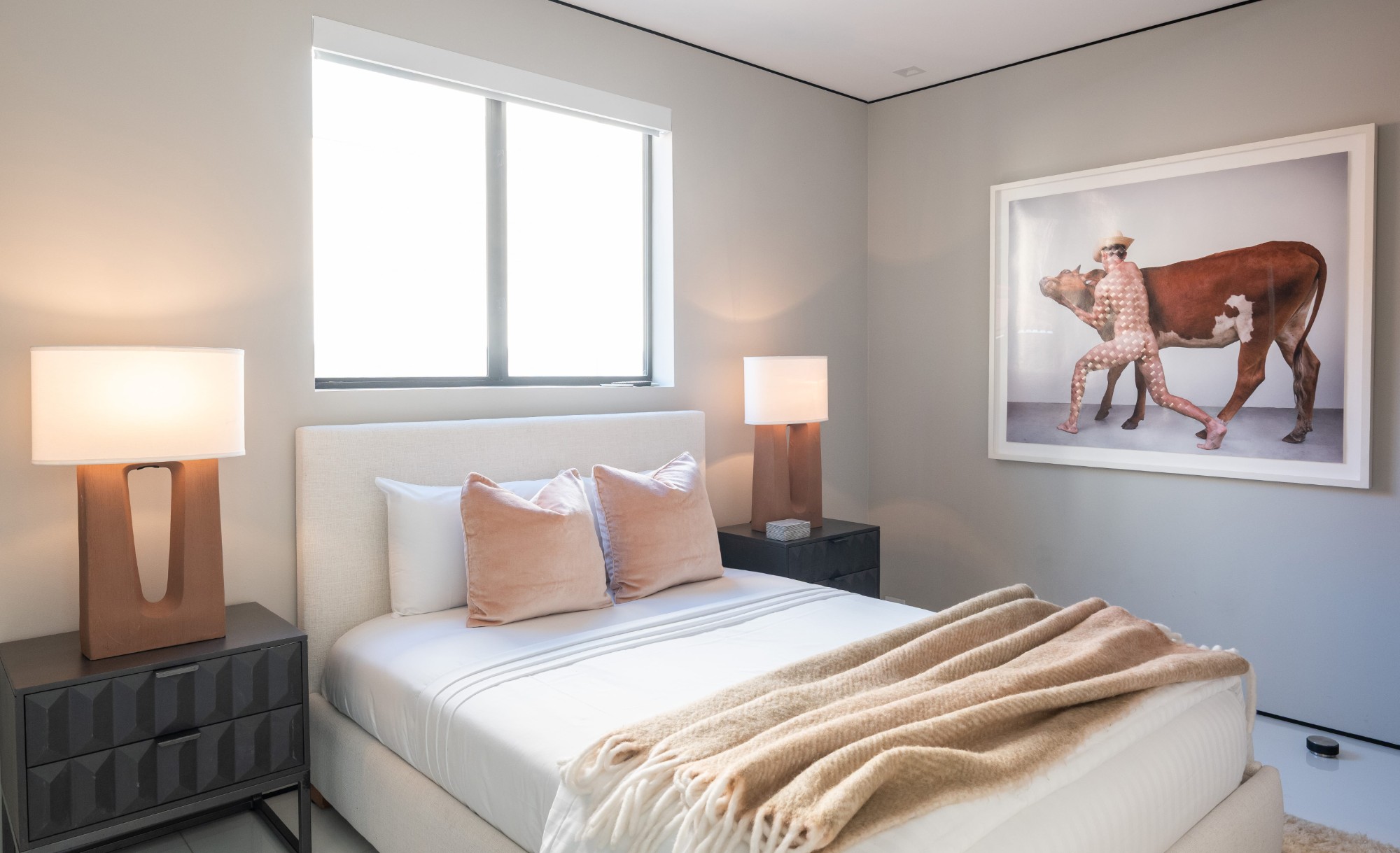 Upstairs guest bedroom 2 with twin lamps, a window above the bed and framed art