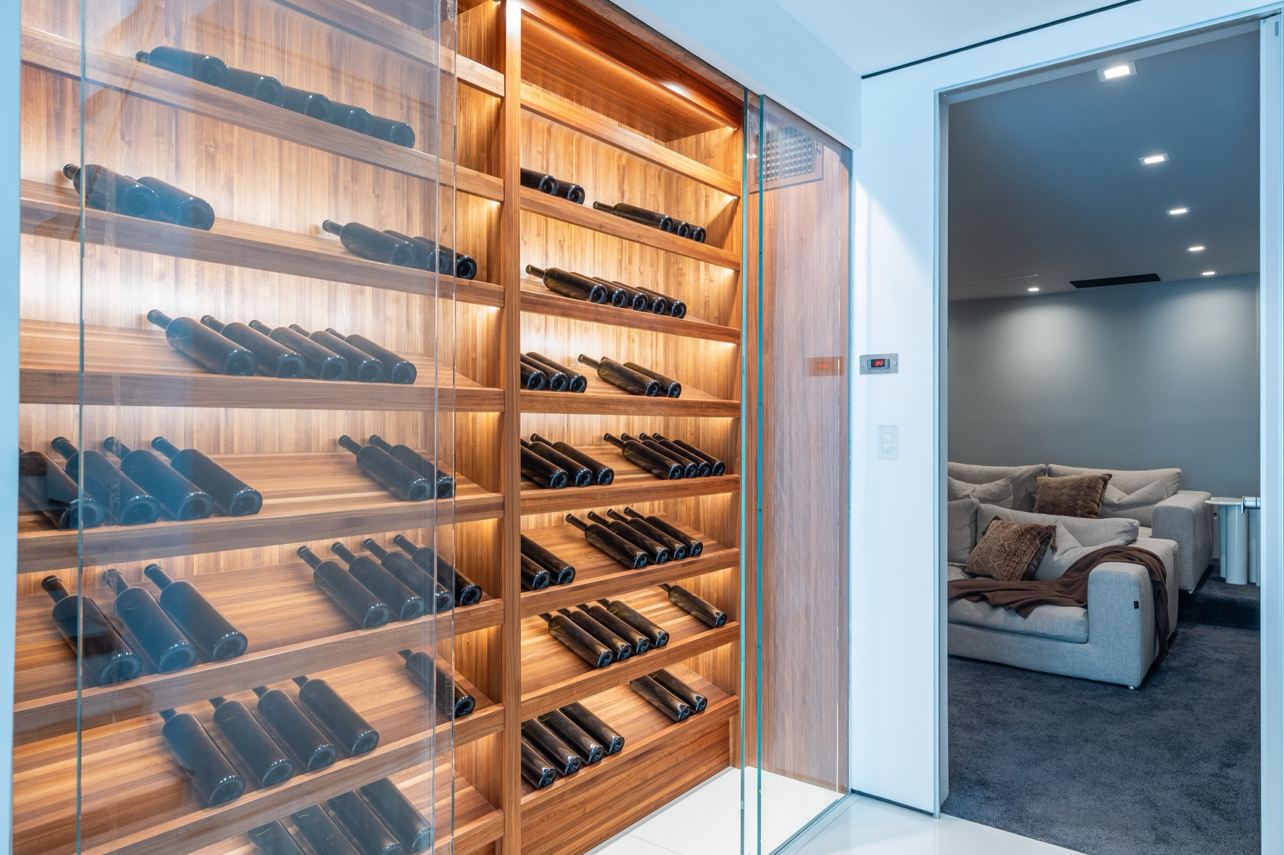 Lit, glass fronted wine wall beside the theater door