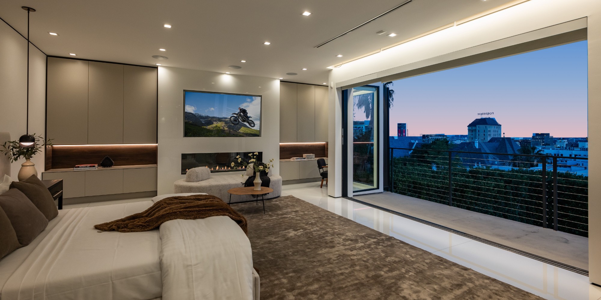 Primary suite at twilight with fireplace and city view